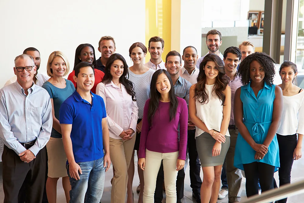 A diverse group of smiling employees standing together in a modern office